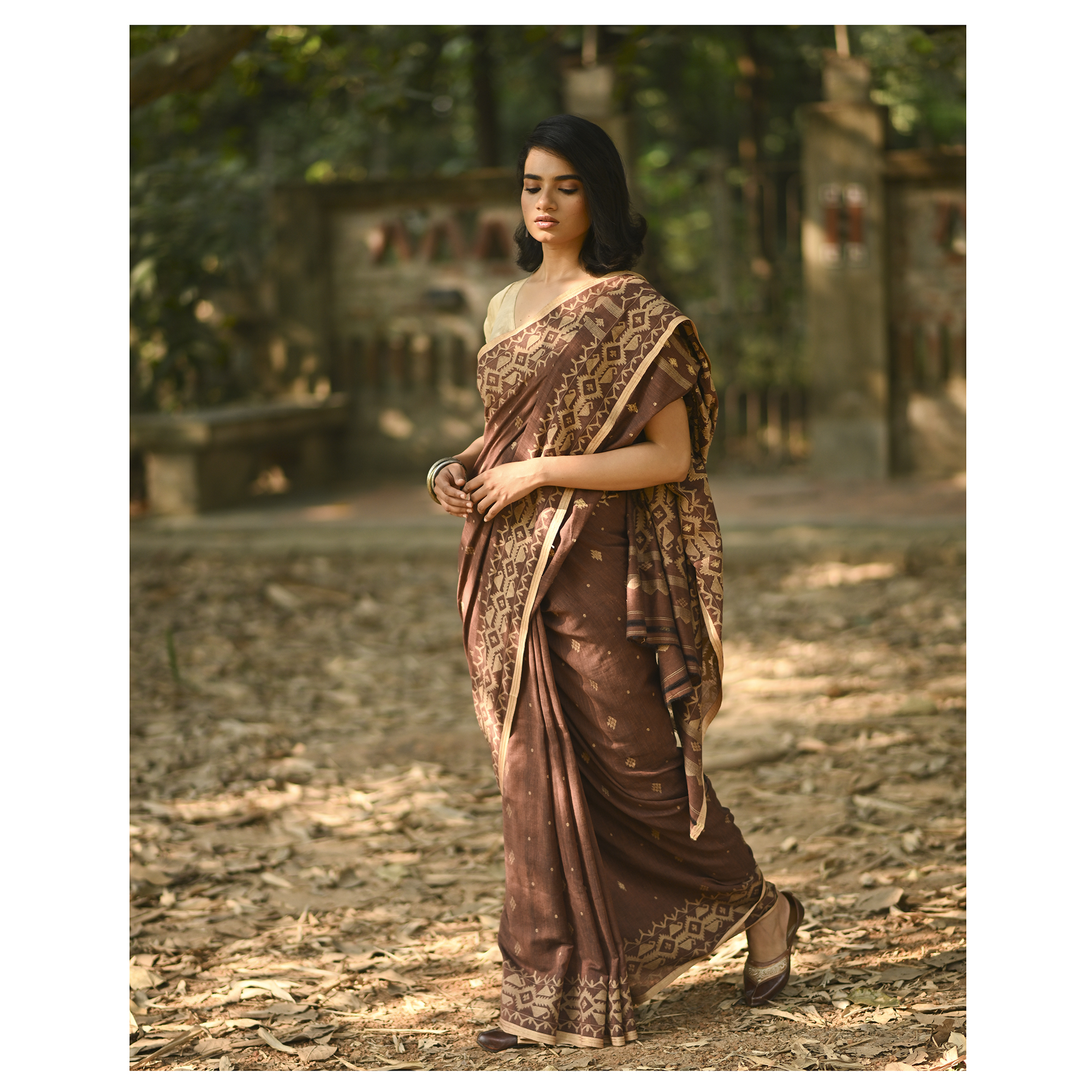 Model wearing the Cocoa Geometry Jamdani Saree, a handwoven deep cocoa brown with sand-beige weave Jamdani saree with geometric body motifs with woven butis and richly worked pallu with bold geometric detailing.