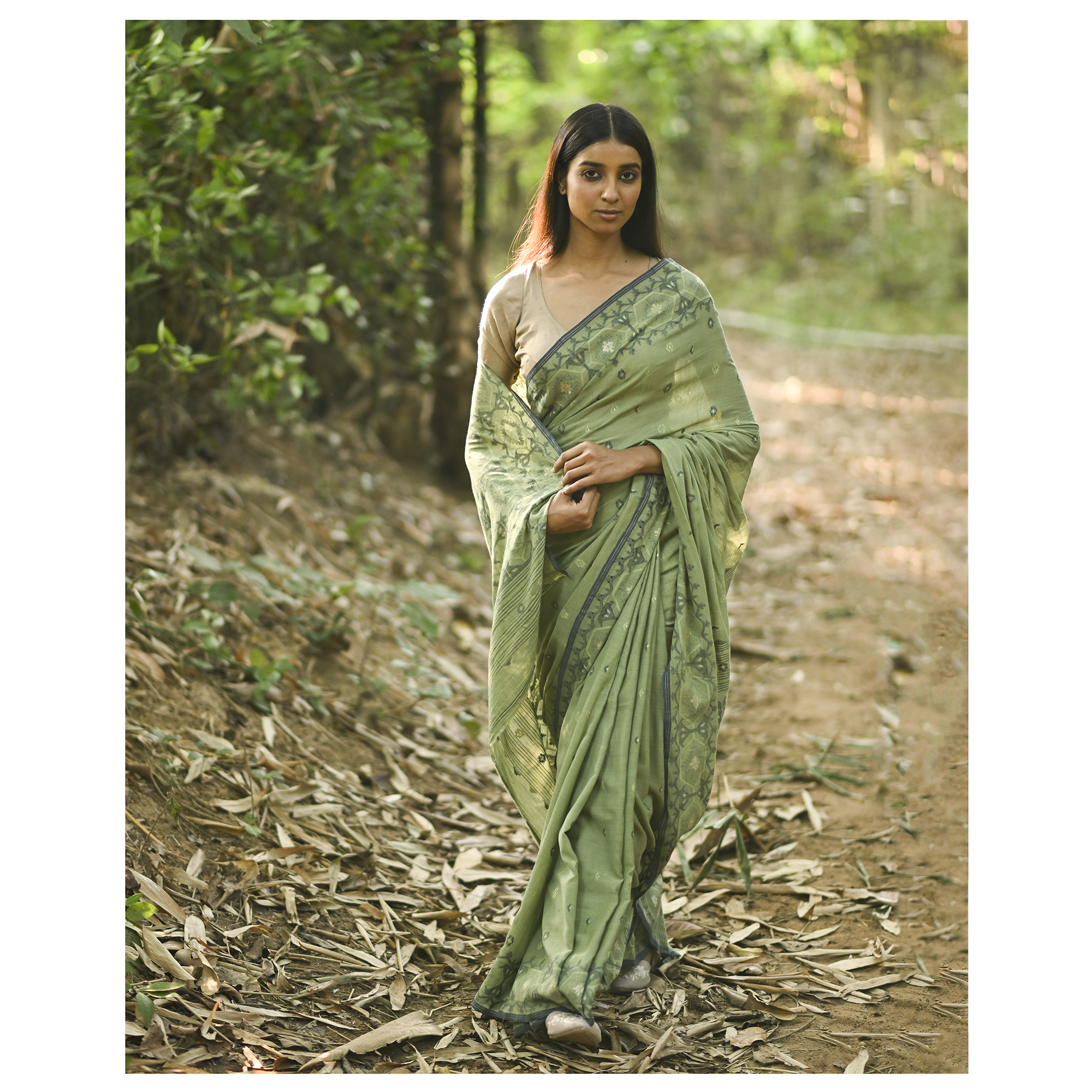 Model wearing the Moss Green Woven Jamdani Saree, a handwoven moss green with deeper woven detailing Jamdani saree with body and pallu woven with darker foliage-like geometry and detailed pallu that echoes shaded, natural textures.