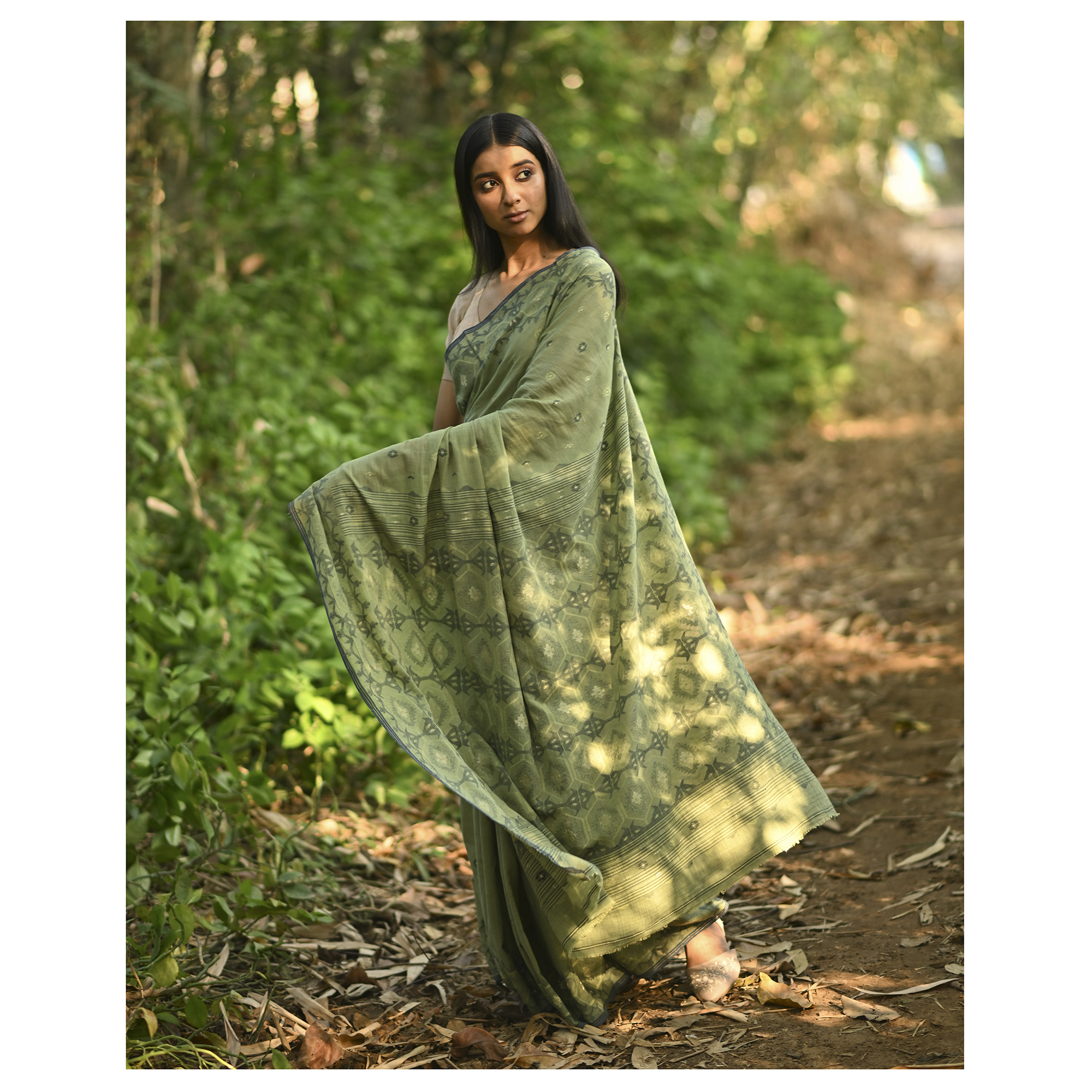 Model wearing the Moss Green Woven Jamdani Saree, a handwoven moss green with deeper woven detailing Jamdani saree with body and pallu woven with darker foliage-like geometry and detailed pallu that echoes shaded, natural textures.