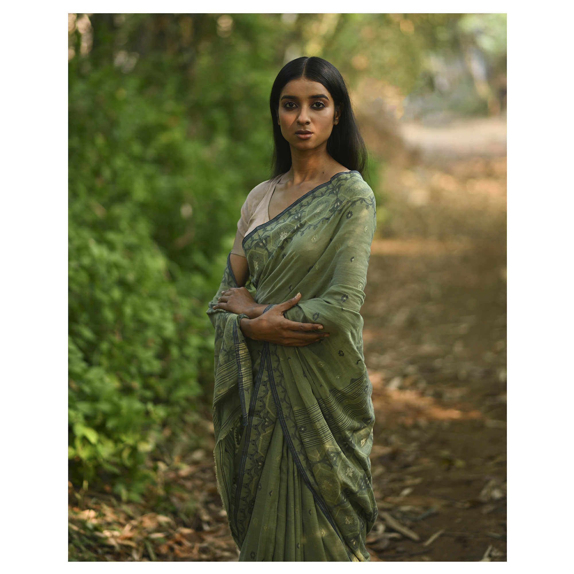 Model wearing the Moss Green Woven Jamdani Saree, a handwoven moss green with deeper woven detailing Jamdani saree with body and pallu woven with darker foliage-like geometry and detailed pallu that echoes shaded, natural textures.