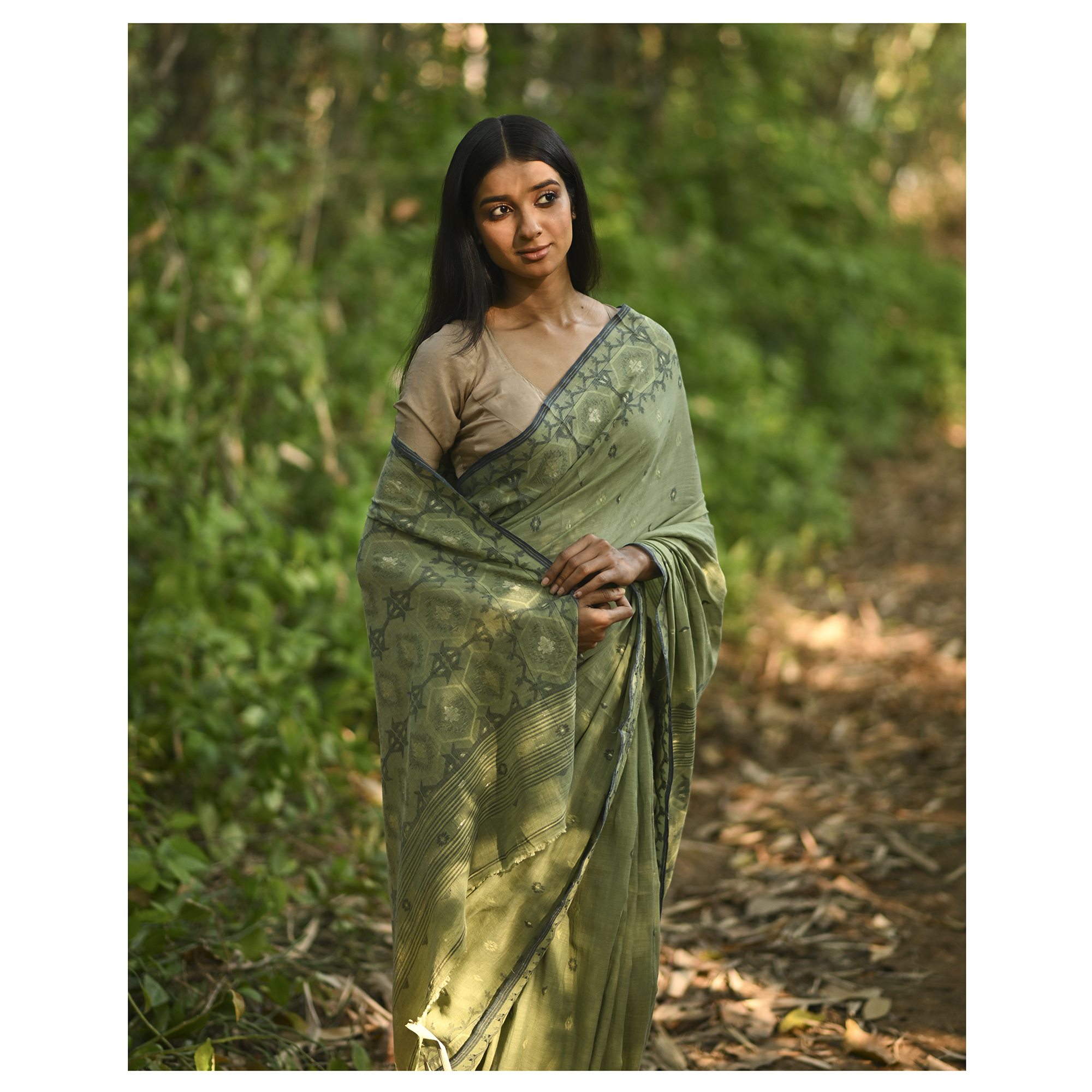 Model wearing the Moss Green Woven Jamdani Saree, a handwoven moss green with deeper woven detailing Jamdani saree with body and pallu woven with darker foliage-like geometry and detailed pallu that echoes shaded, natural textures.