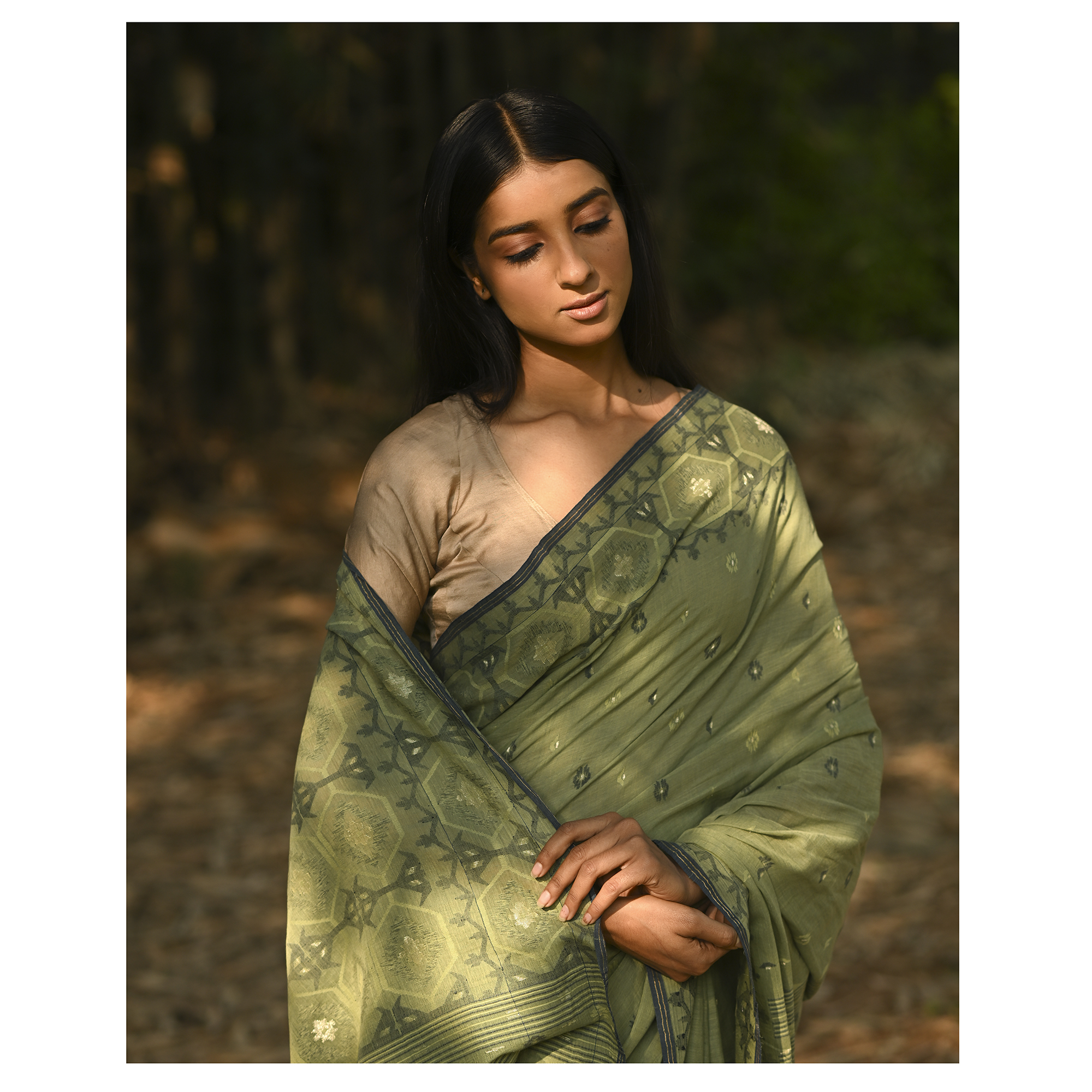 Model wearing the Moss Green Woven Jamdani Saree, a handwoven moss green with deeper woven detailing Jamdani saree with body and pallu woven with darker foliage-like geometry and detailed pallu that echoes shaded, natural textures.