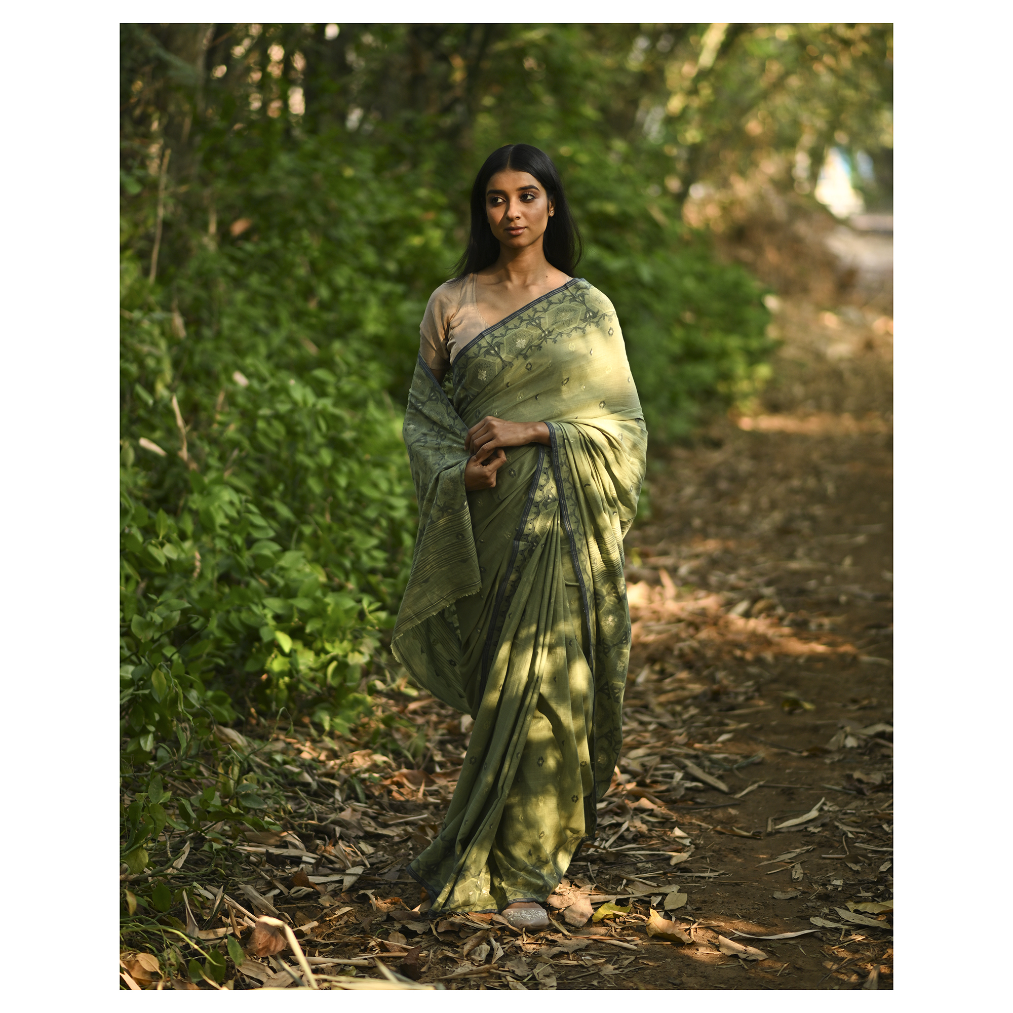 Model wearing the Moss Green Woven Jamdani Saree, a handwoven moss green with deeper woven detailing Jamdani saree with body and pallu woven with darker foliage-like geometry and detailed pallu that echoes shaded, natural textures.