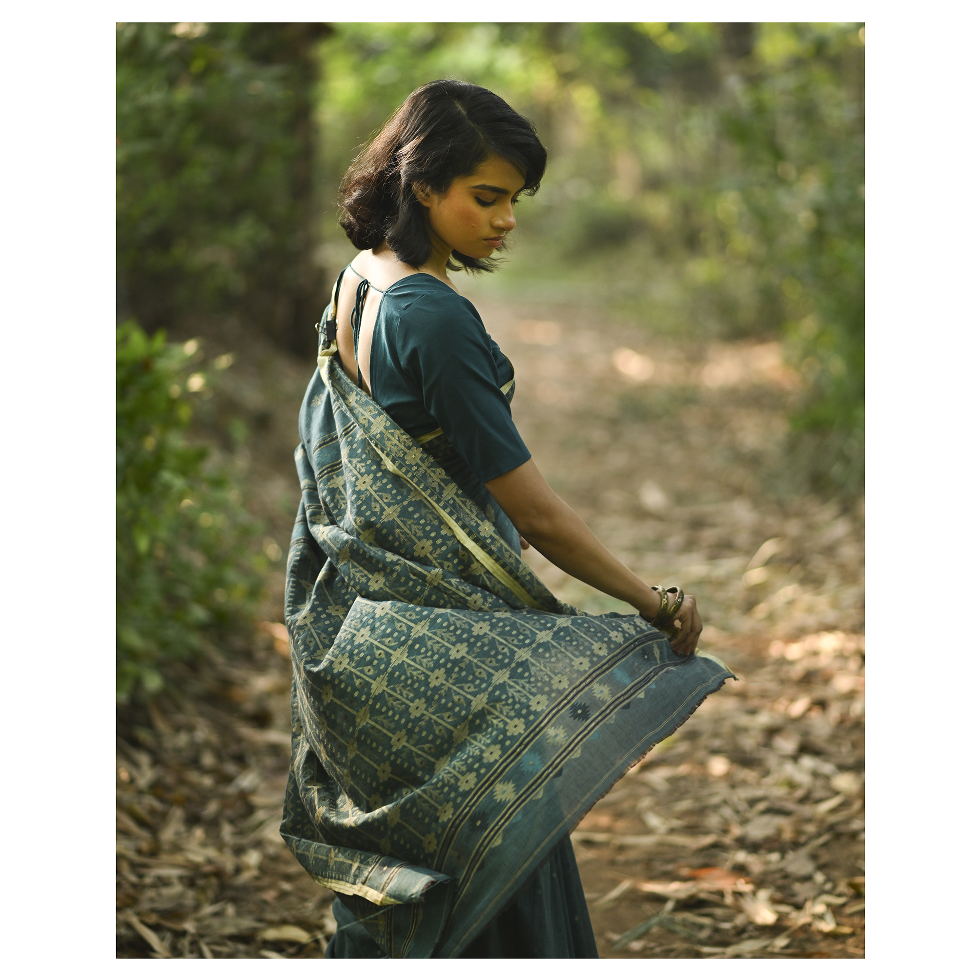 Model wearing the Teal Antique-Gold Jamdani Saree, a handwoven deep teal with antique-gold weaving Jamdani saree with fine woven motifs and classic border detailing and intricately woven pallu with festive sheen.