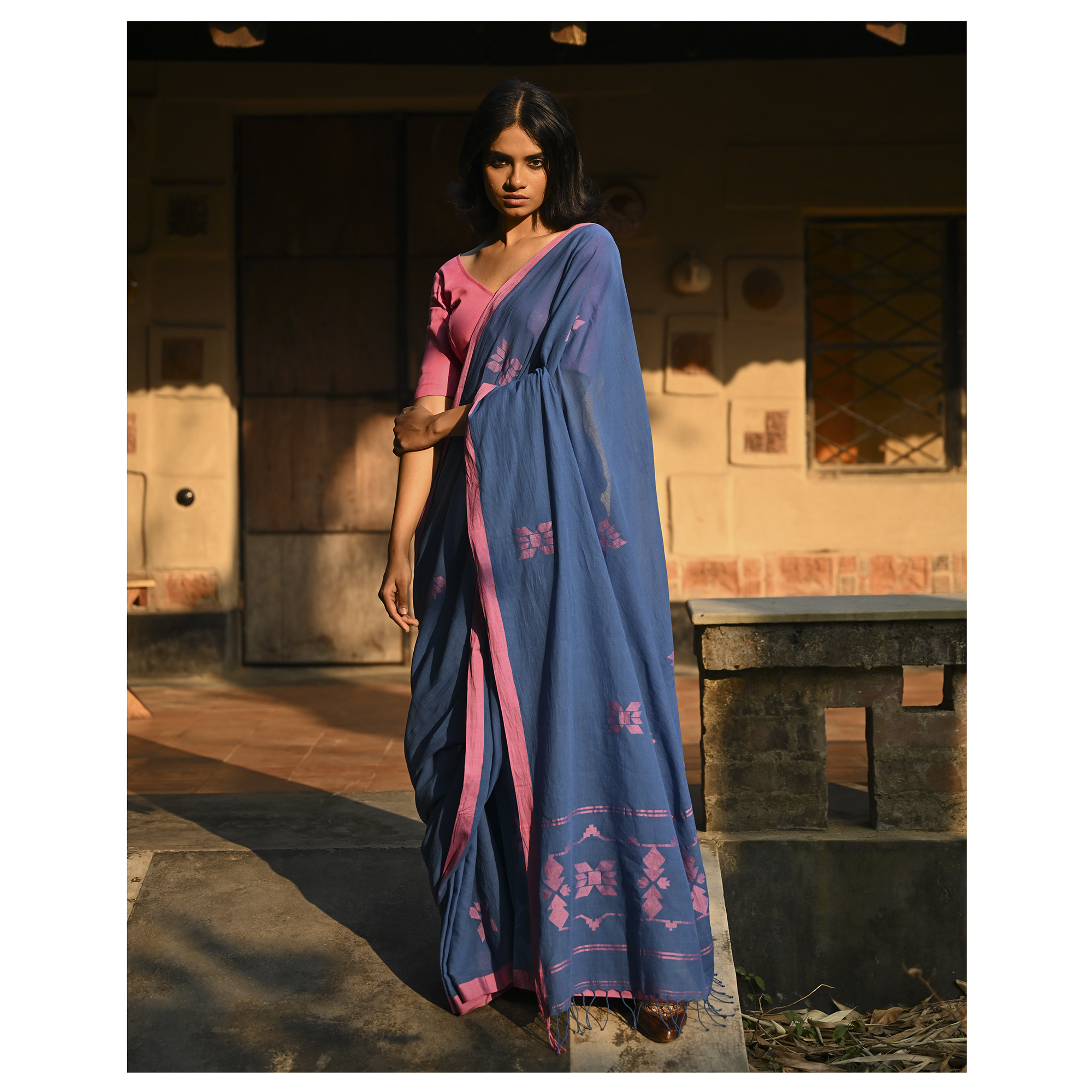 Model wearing the Indigo Blush Jamdani Saree, a handwoven moody indigo with blush-pink accents Jamdani saree with subtle woven motifs highlighted with blush contrast and border-led pallu with restrained pink detailing.