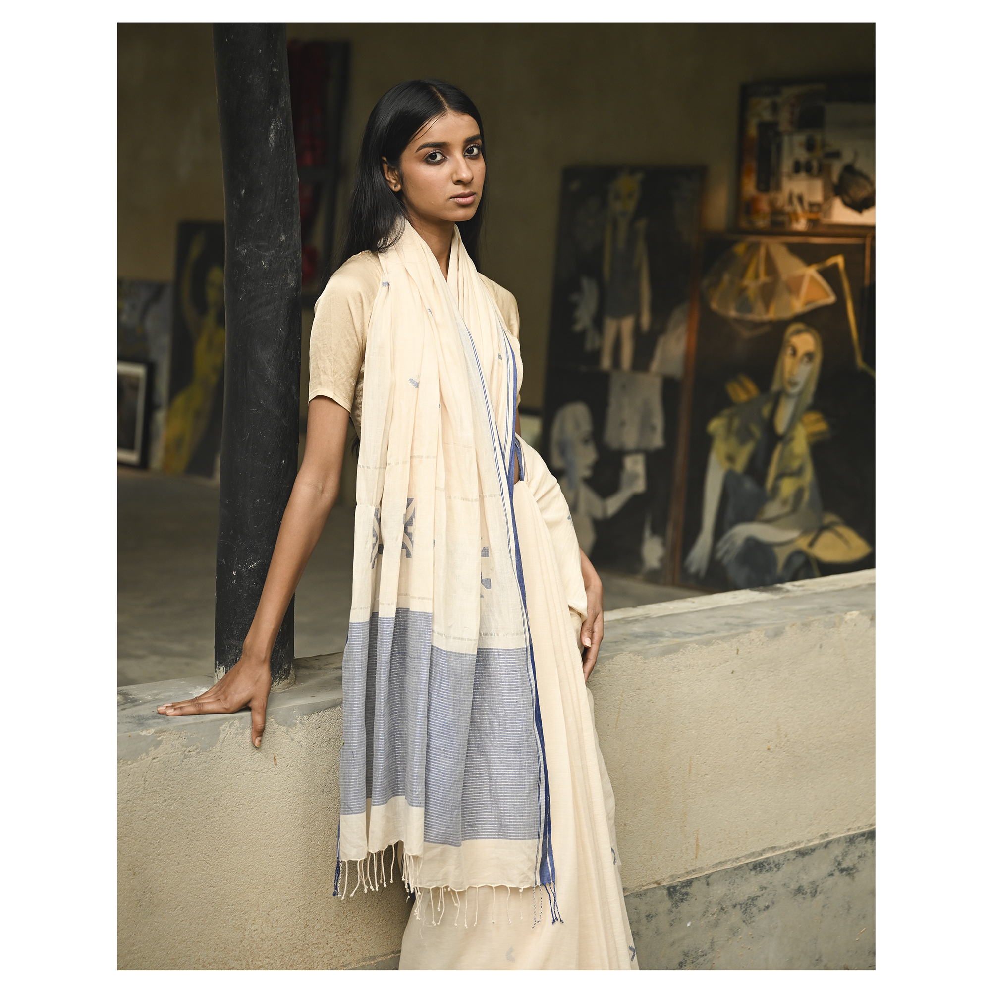 Model wearing the Ivory Blue-Border Jamdani Saree, a handwoven soft ivory with muted blue border accents Jamdani saree with minimal woven accents with quiet buti work and clean pallu framed by a restrained blue border.