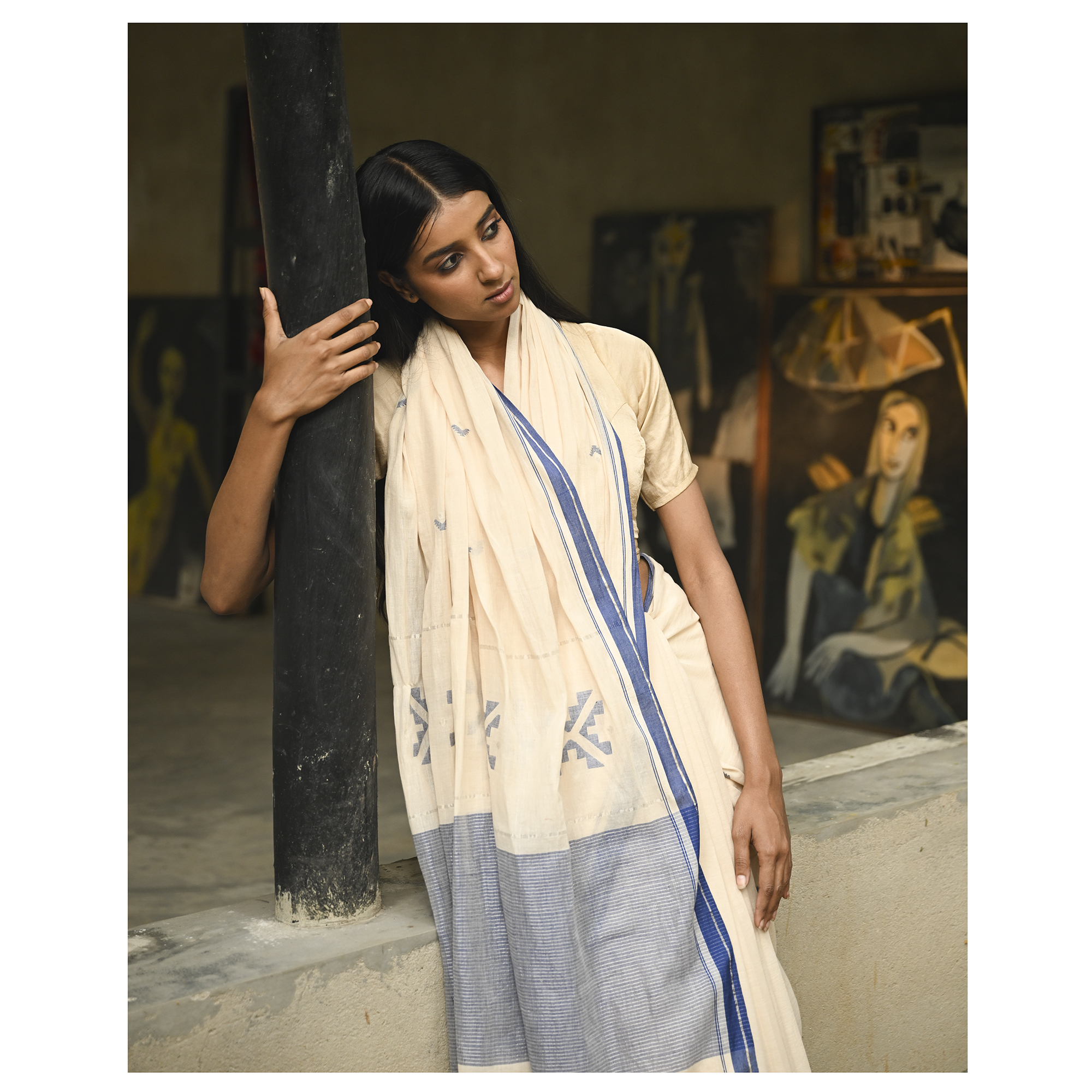 Model wearing the Ivory Blue-Border Jamdani Saree, a handwoven soft ivory with muted blue border accents Jamdani saree with minimal woven accents with quiet buti work and clean pallu framed by a restrained blue border.