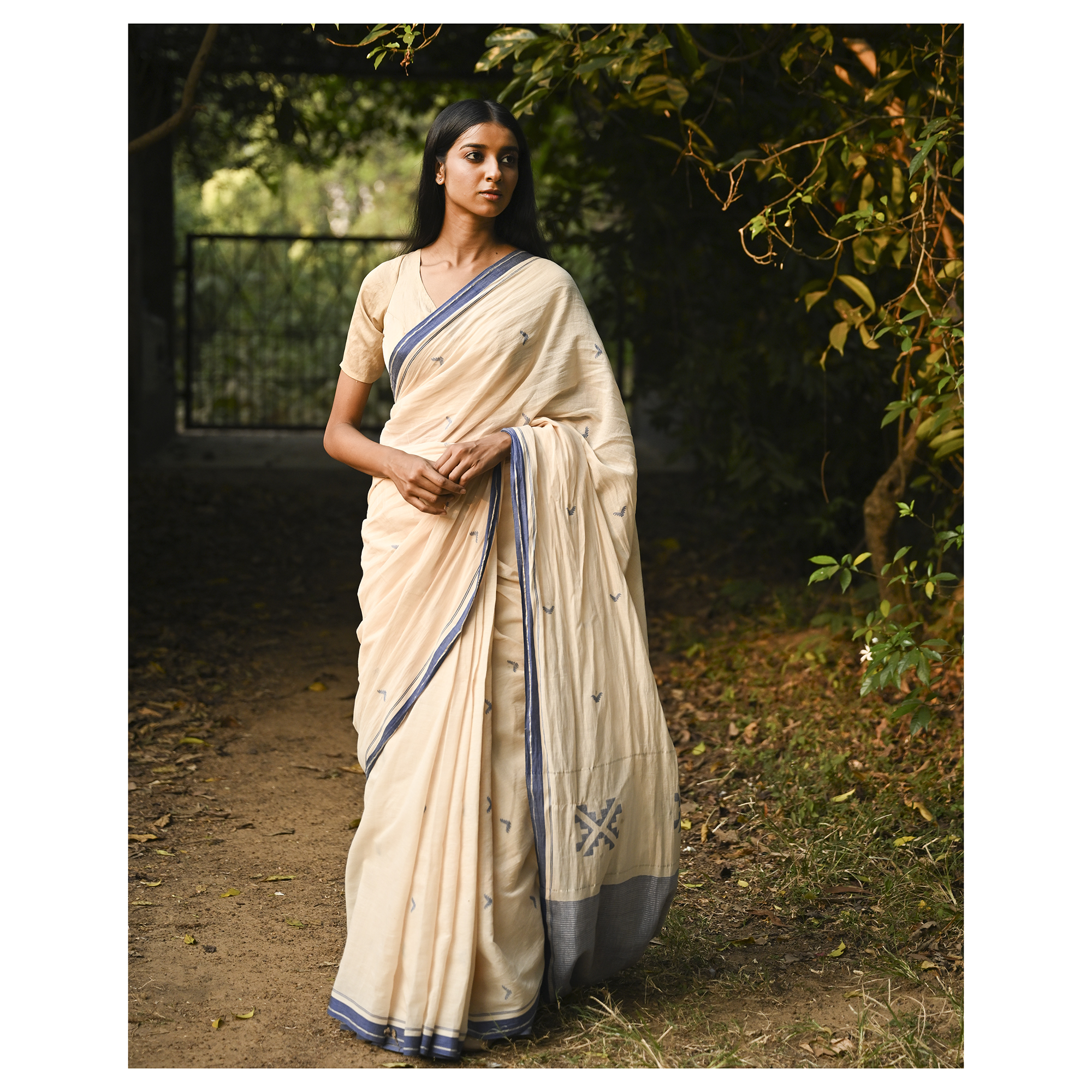 Model wearing the Ivory Blue-Border Jamdani Saree, a handwoven soft ivory with muted blue border accents Jamdani saree with minimal woven accents with quiet buti work and clean pallu framed by a restrained blue border.