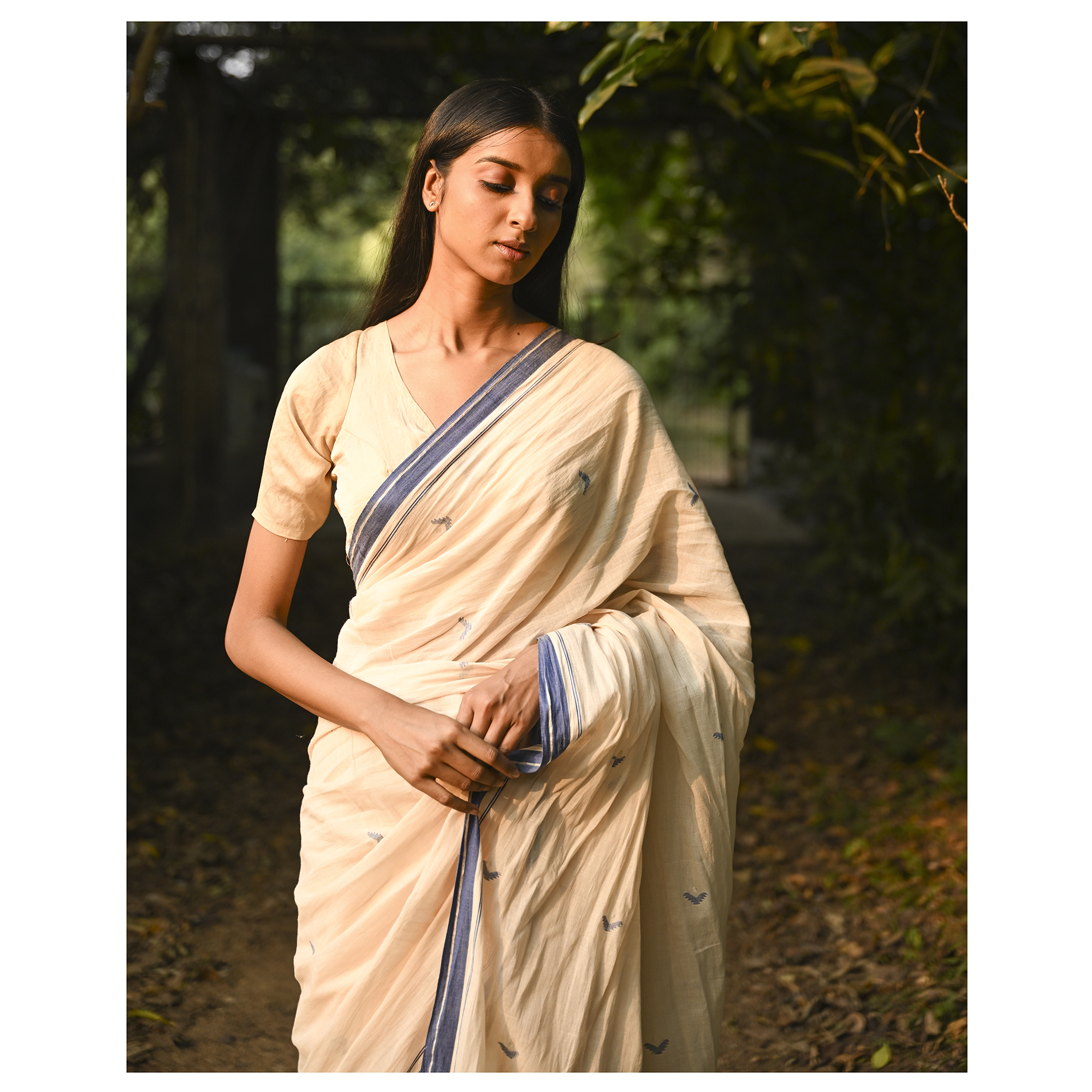Model wearing the Ivory Blue-Border Jamdani Saree, a handwoven soft ivory with muted blue border accents Jamdani saree with minimal woven accents with quiet buti work and clean pallu framed by a restrained blue border.