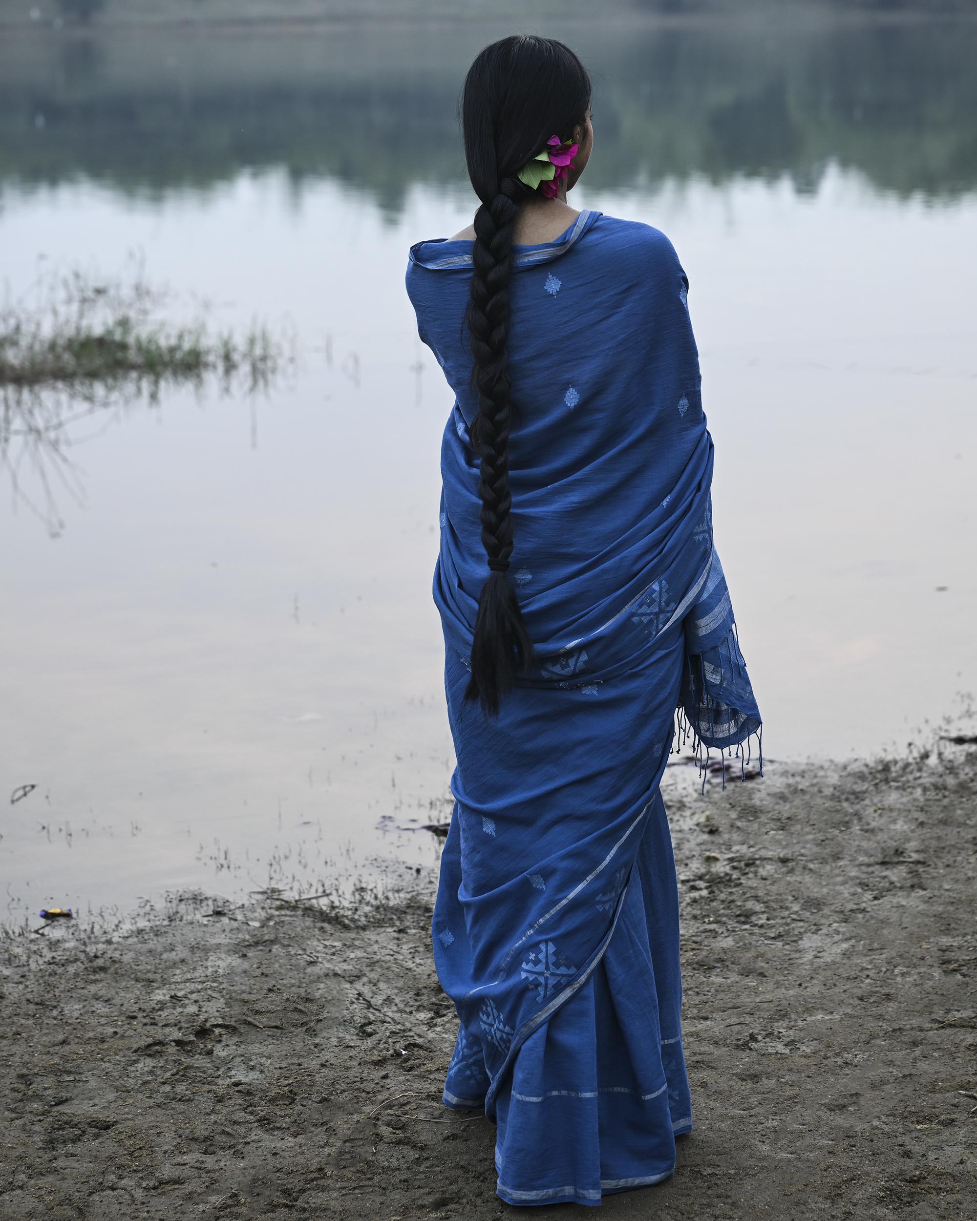 Model wearing the Dusty Blue Minimal Jamdani Saree, a handwoven dusty blue with a softly lustrous border Jamdani saree with sparse woven buttis with a minimal body and subtle pallu that mirrors the quiet elegance of the body.