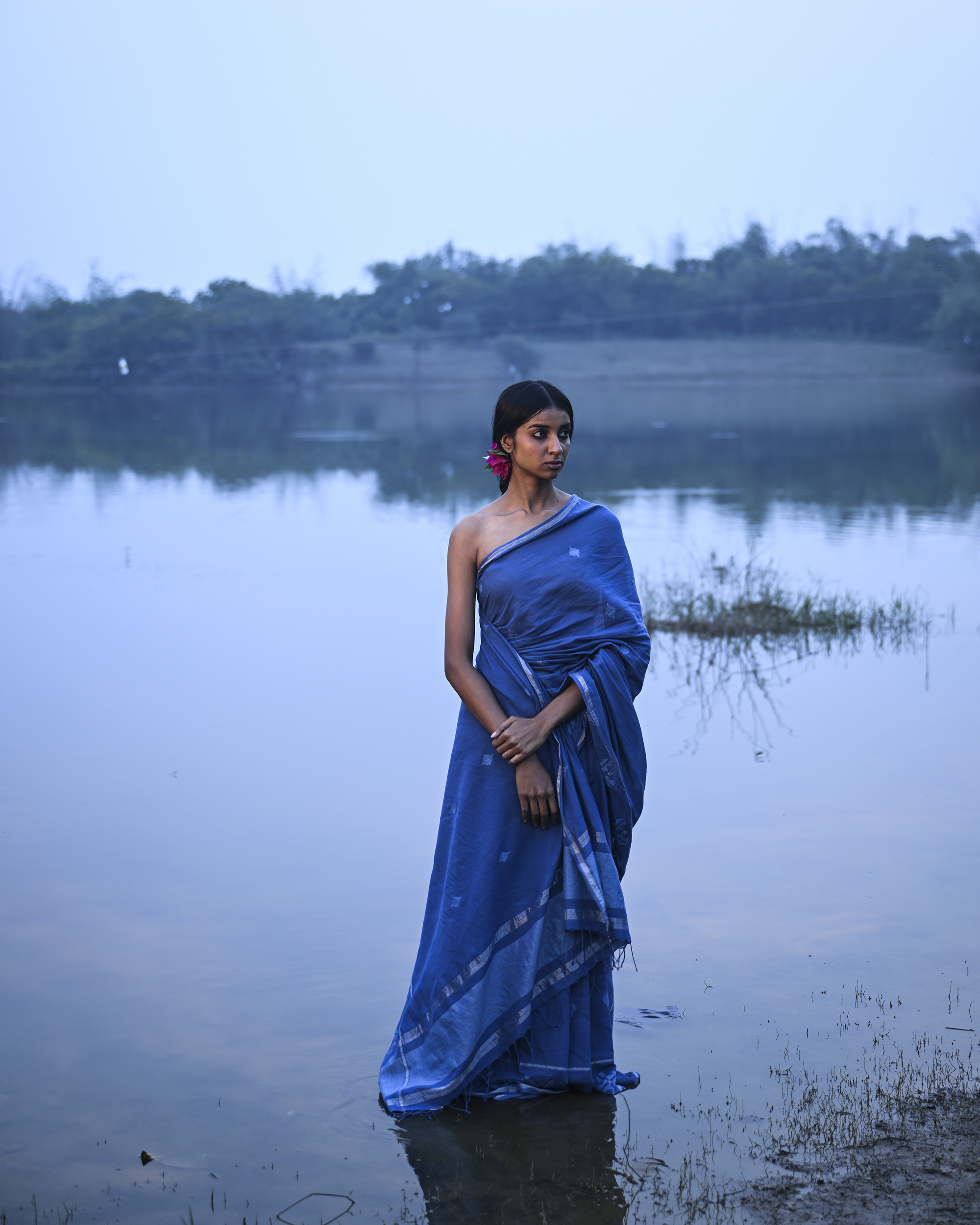 Model wearing the Dusty Blue Minimal Jamdani Saree, a handwoven dusty blue with a softly lustrous border Jamdani saree with sparse woven buttis with a minimal body and subtle pallu that mirrors the quiet elegance of the body.