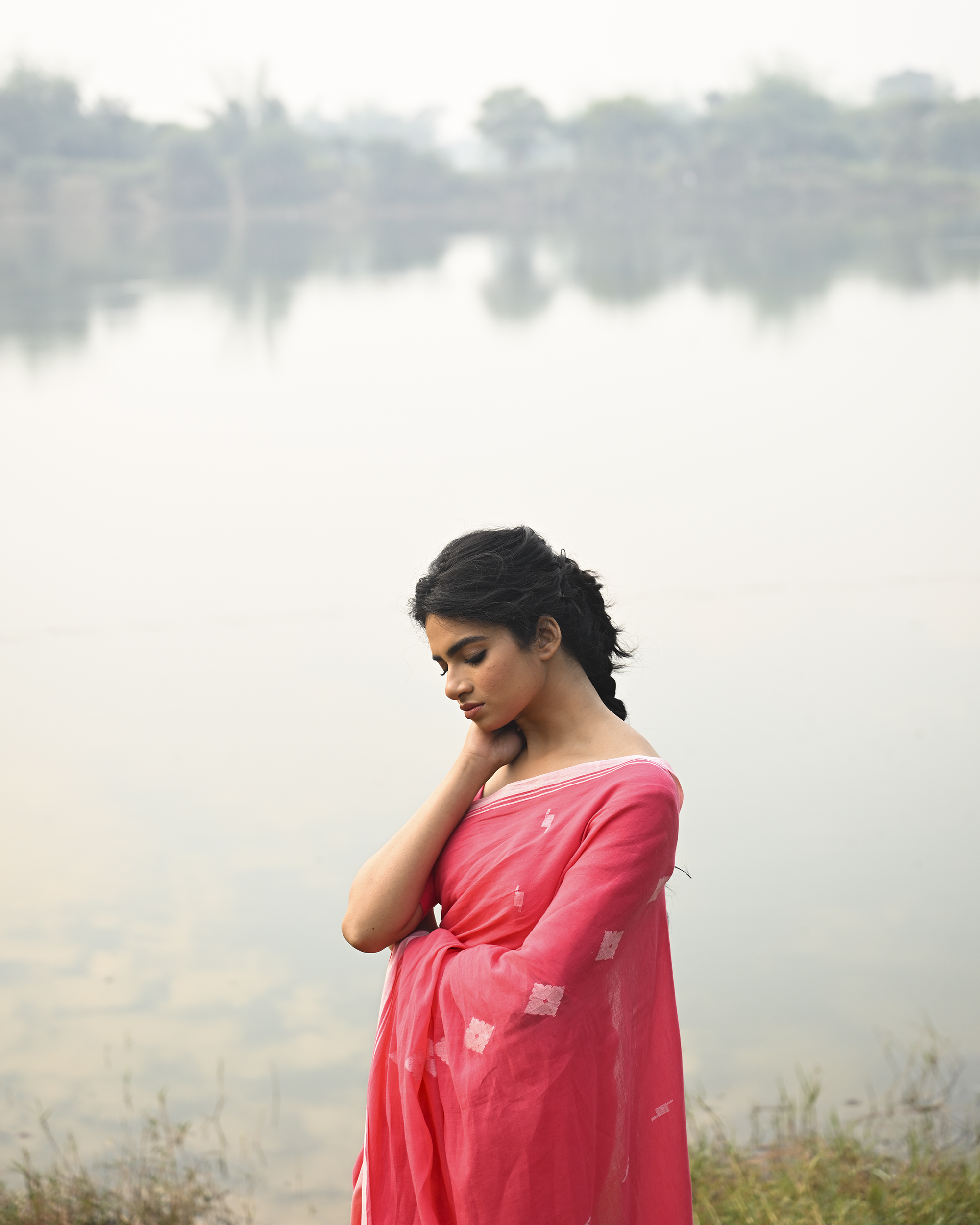 Model wearing the Coral Buti Jamdani Saree, a handwoven fresh coral-pink with white motifs Jamdani saree with tiny white butis scattered across the body and softly open pallu with delicate woven detail.