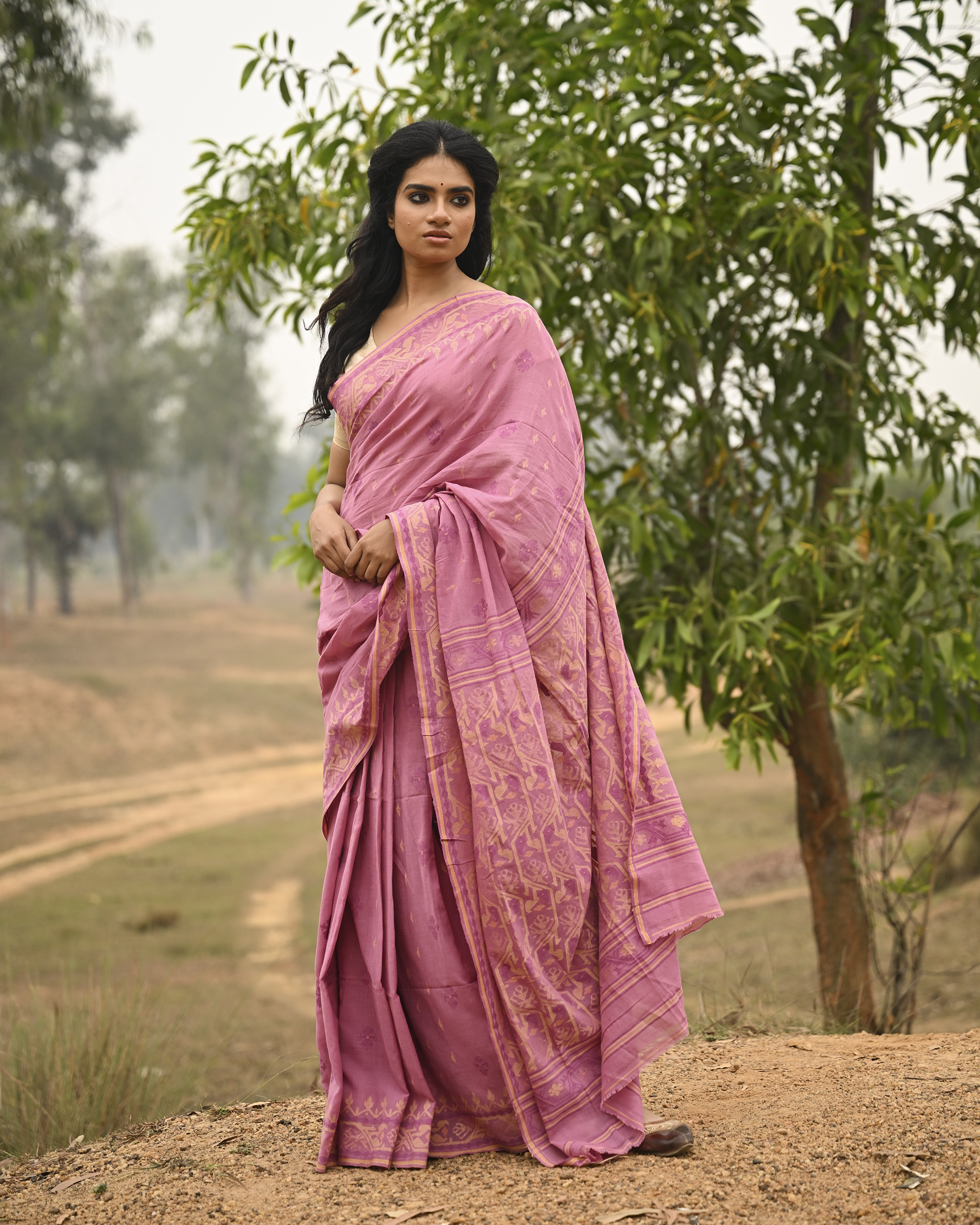 Model wearing the Mauve Gold-Detail Jamdani Saree, a handwoven muted mauve with soft gold detailing Jamdani saree with gentle woven motifs with a graceful festive border and elegant pallu with understated gold-rich work.