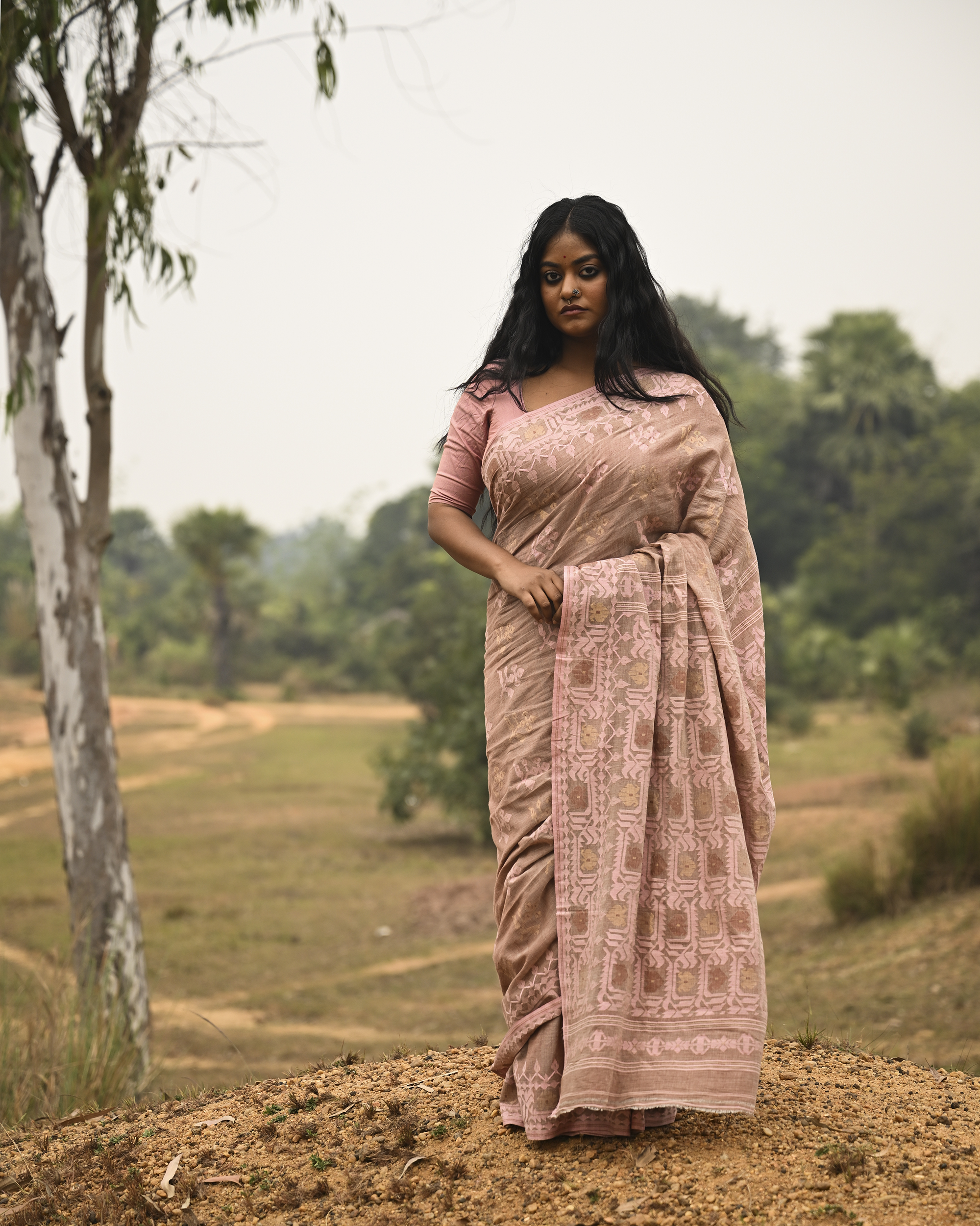 Model wearing the Blush Nude Pastel Jamdani Saree, a handwoven blush nude with pastel rose and muted gold weave Jamdani saree with rich woven body and border work with soft pastel accents and heavily detailed pallu made to be worn open.