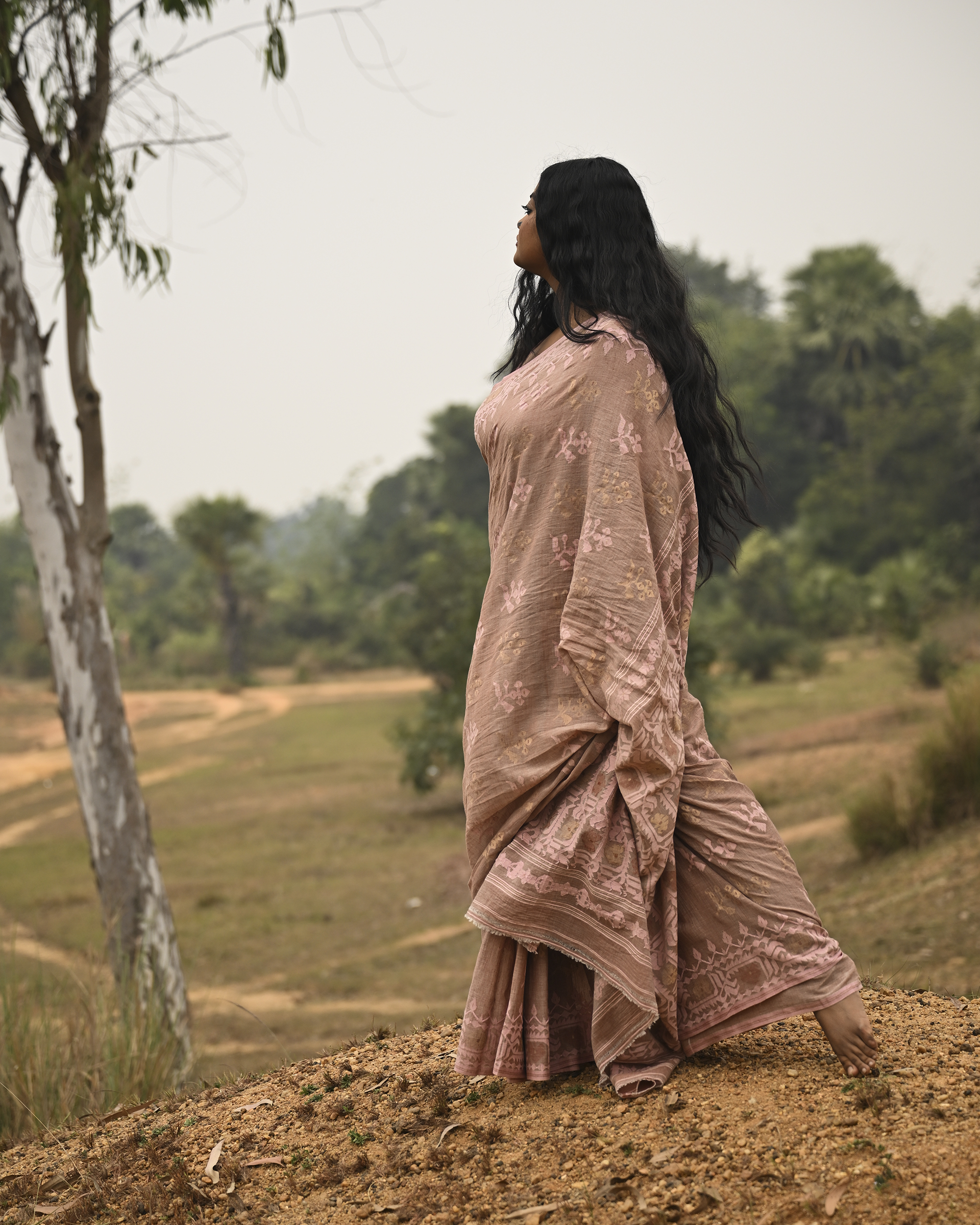 Model wearing the Blush Nude Pastel Jamdani Saree, a handwoven blush nude with pastel rose and muted gold weave Jamdani saree with rich woven body and border work with soft pastel accents and heavily detailed pallu made to be worn open.