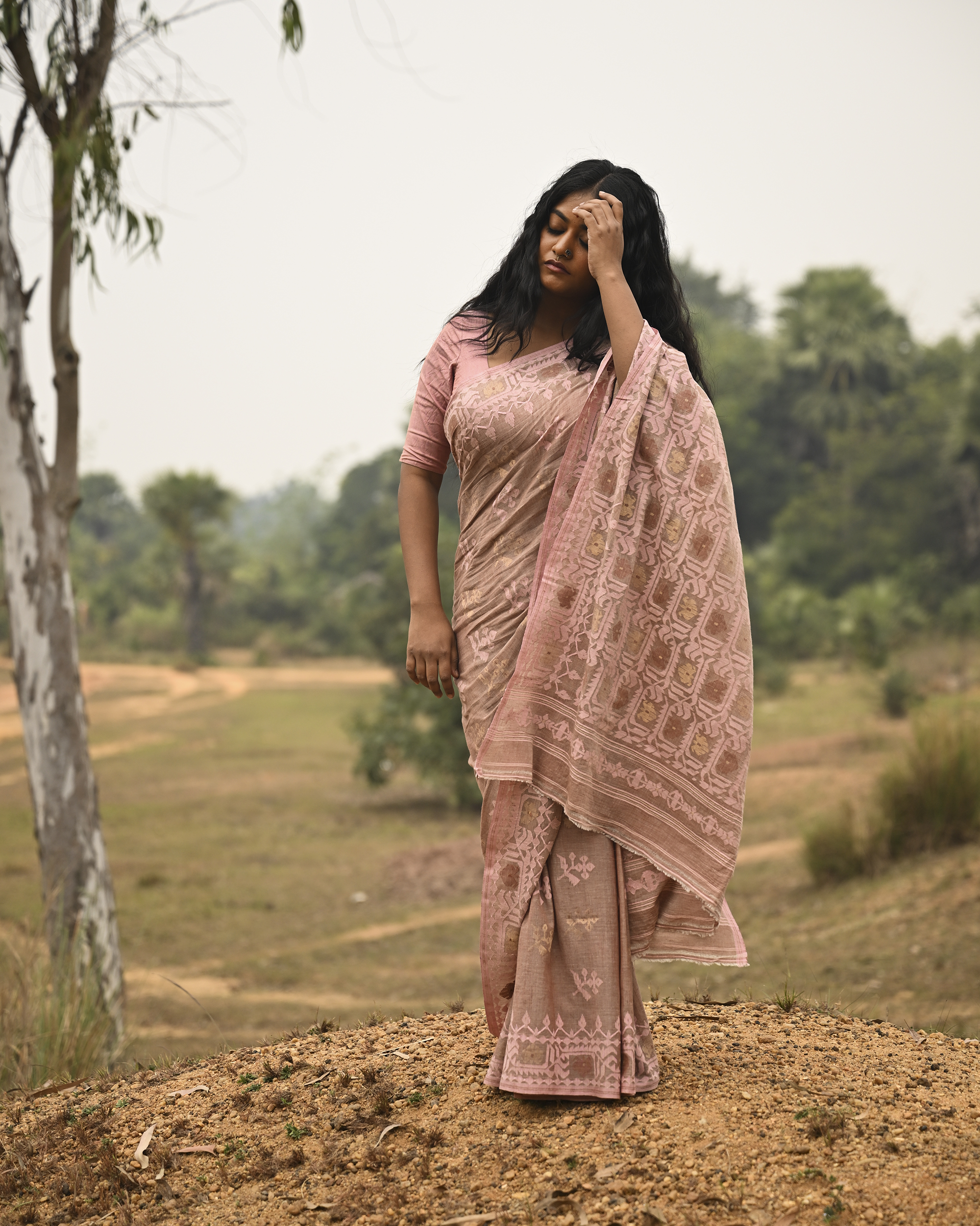 Model wearing the Blush Nude Pastel Jamdani Saree, a handwoven blush nude with pastel rose and muted gold weave Jamdani saree with rich woven body and border work with soft pastel accents and heavily detailed pallu made to be worn open.