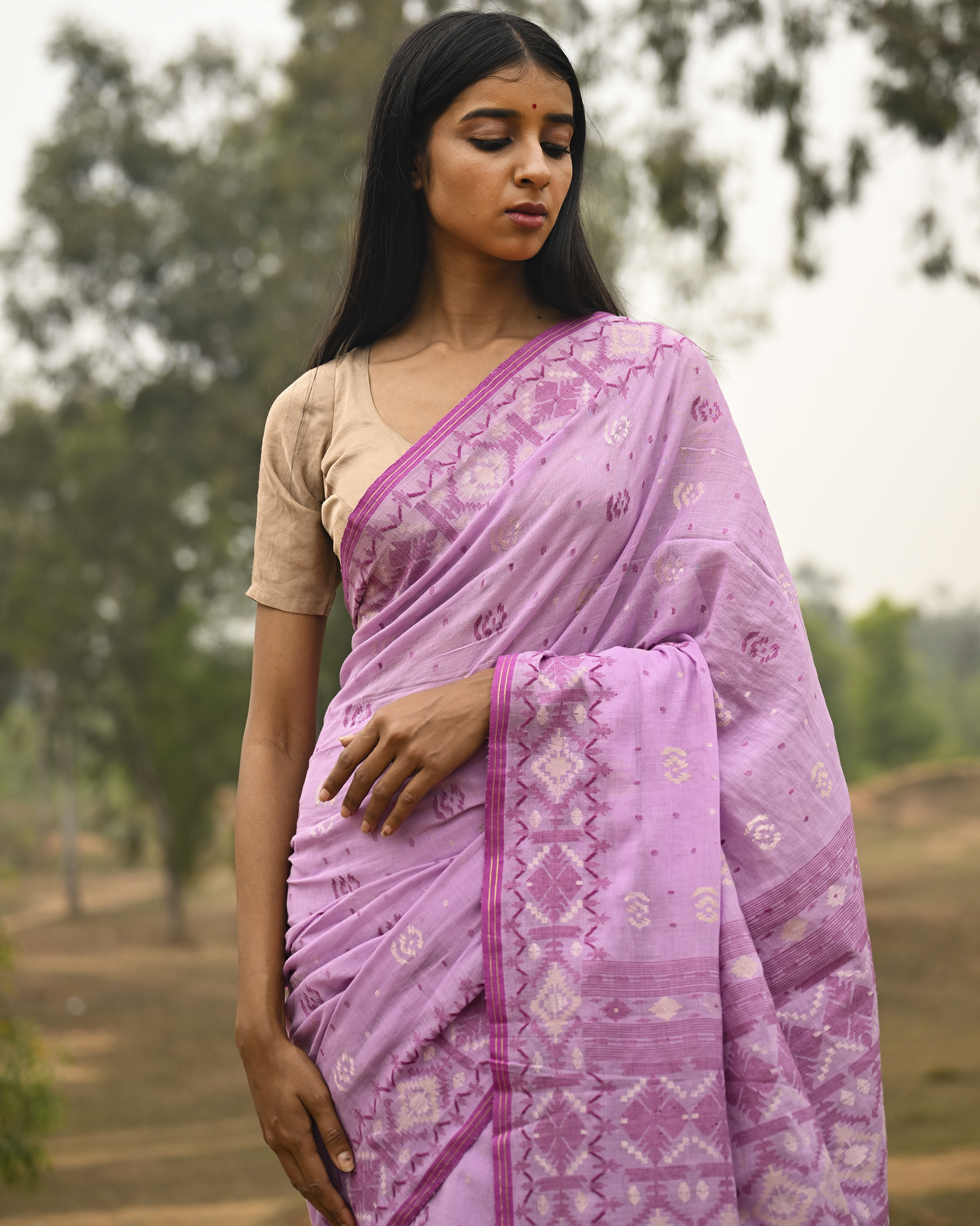 Model wearing the Lilac Silver-Pink Jamdani Saree, a handwoven luminous lilac with silvery-pink weaving Jamdani saree with scattered motifs with a softly ornate weave language and ornate pallu with luminous woven detailing.