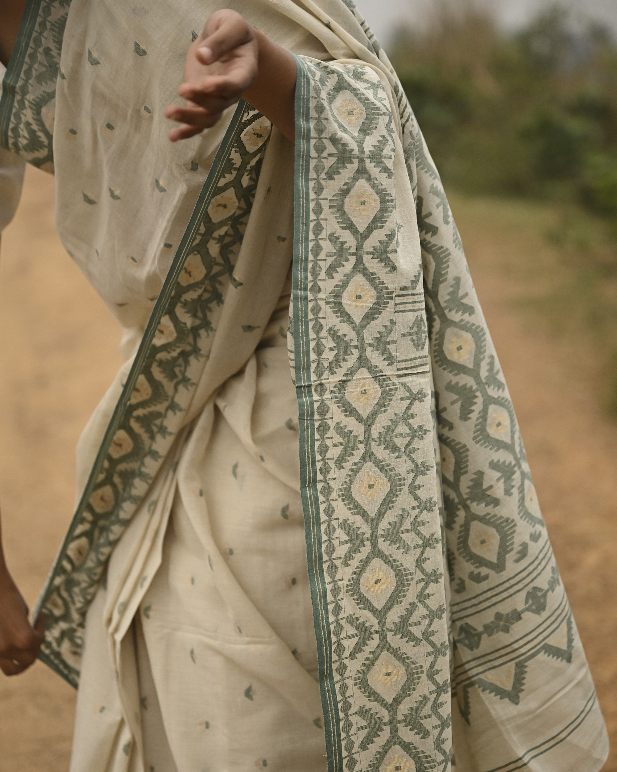 Model wearing the Ivory Sage Pallu Jamdani Saree, a handwoven soft ivory with sage-green edging Jamdani saree with subtle body motifs with architectural woven detailing and beautifully patterned pallu edged in sage-green weaving.