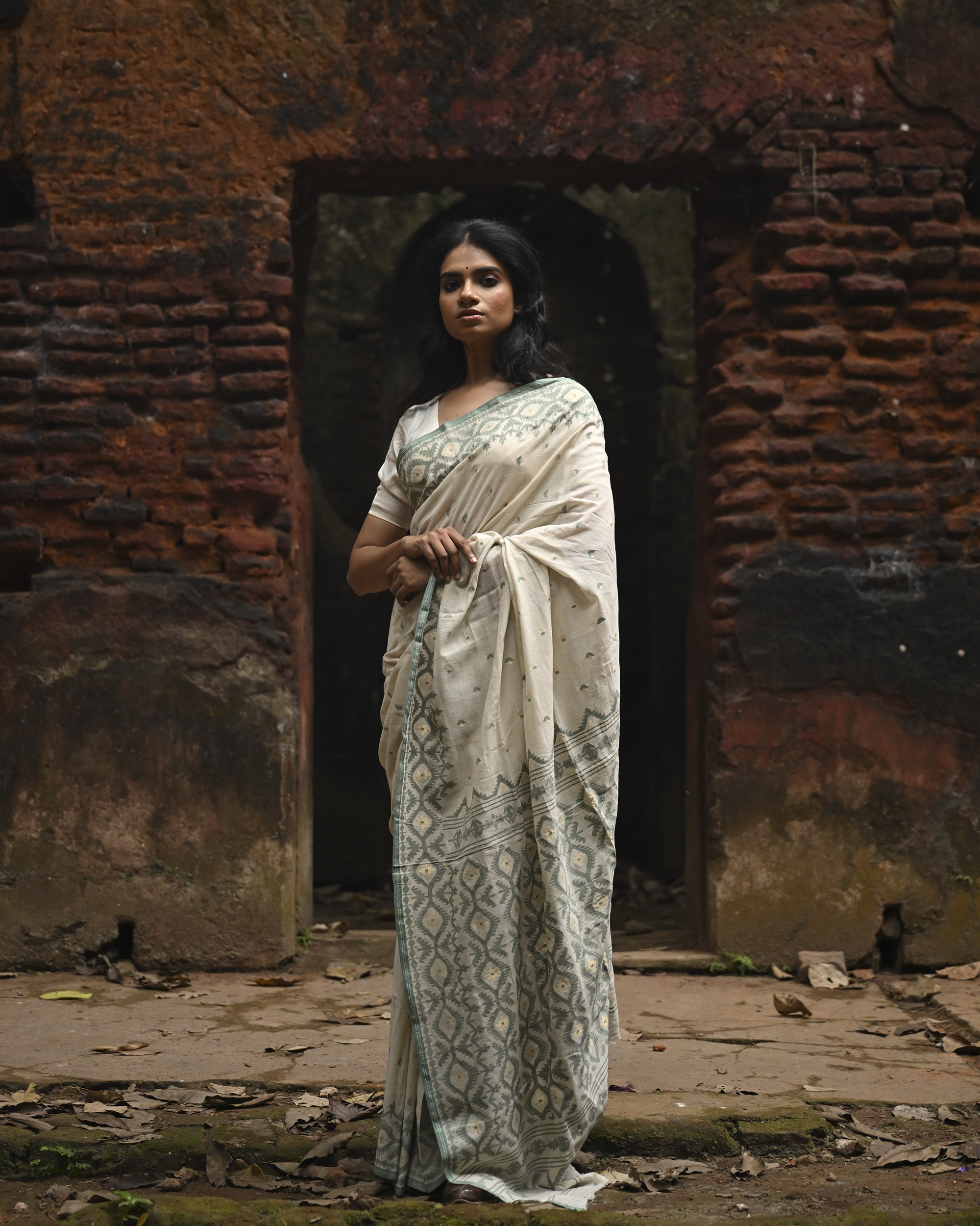 Model wearing the Ivory Sage Pallu Jamdani Saree, a handwoven soft ivory with sage-green edging Jamdani saree with subtle body motifs with architectural woven detailing and beautifully patterned pallu edged in sage-green weaving.